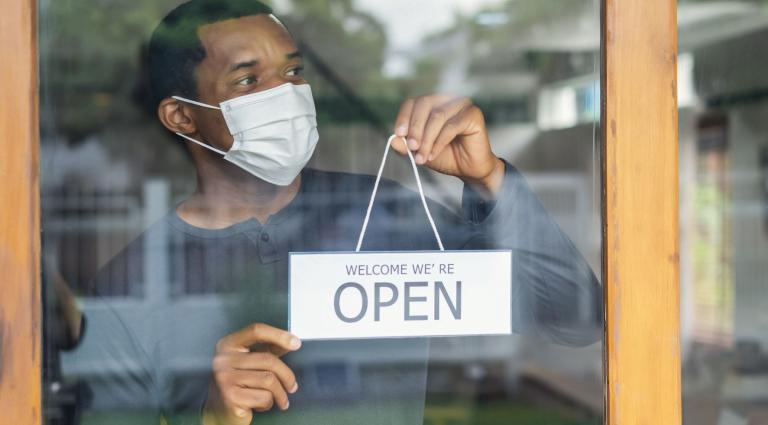 businessman with face mask holding an open sign